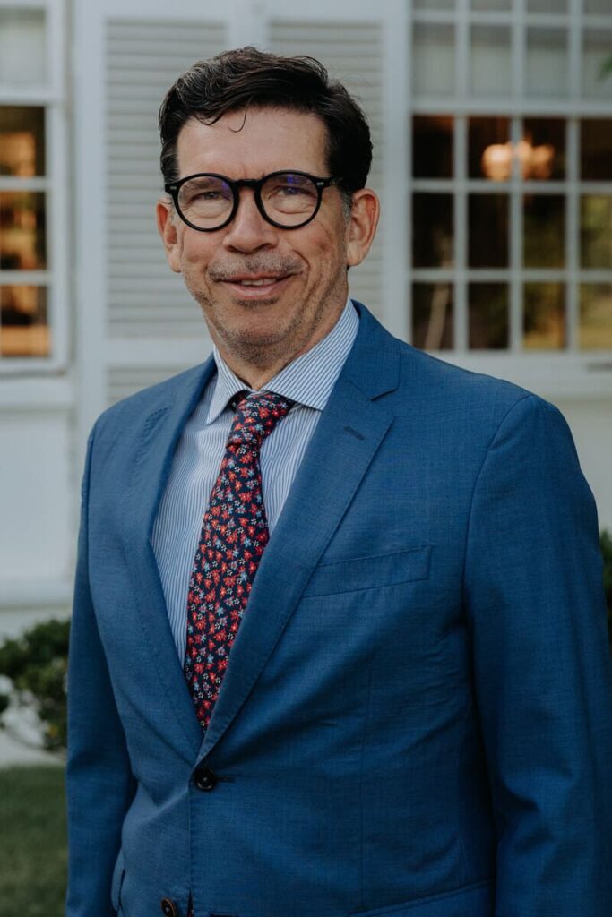 Foto de medio cuerpo de Joaquín García-San Juan. Abundante pelo negro. Gafas negras. Chaqueta azul, camisa a rallas blancas y azules. Corbata en rojo oscuro. Al fondo, algo borrosas, dos ventanas del club.